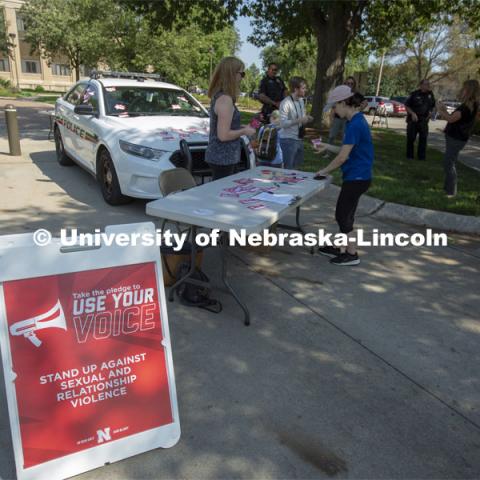 Students sign a "Use Your Voice" pledge and affix them to a police car during the September 10 Cover the Cruiser event on East Campus. More than 75 students, faculty and staff made a pledge to stand up to sexual violence in the first day of the initiative. The Cover the Cruiser events continue Sept. 12 and 13. Both events are 10:30 a.m. to 2 p.m. on the Nebraska Union Plaza. September 10, 2019. Photo by Troy Fedderson / University Communication